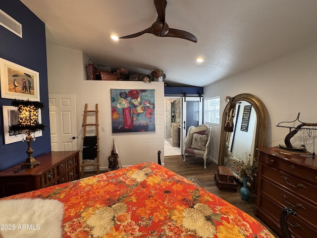 bedroom featuring ceiling fan, a barn door, and dark hardwood / wood-style floors