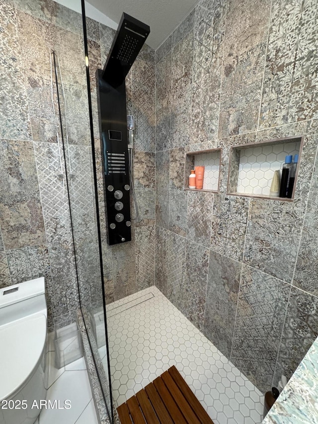 bathroom with a tile shower and tile patterned flooring