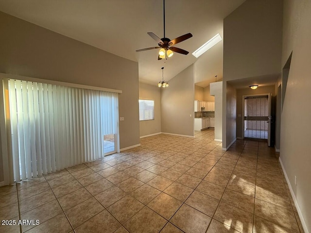 empty room featuring high vaulted ceiling, ceiling fan, baseboards, and light tile patterned flooring