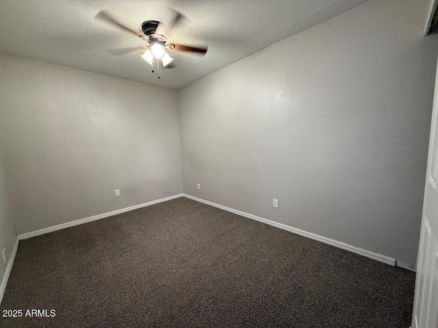 spare room featuring a textured ceiling, dark colored carpet, a ceiling fan, and baseboards