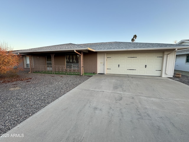 ranch-style house with a garage, covered porch, brick siding, driveway, and roof with shingles