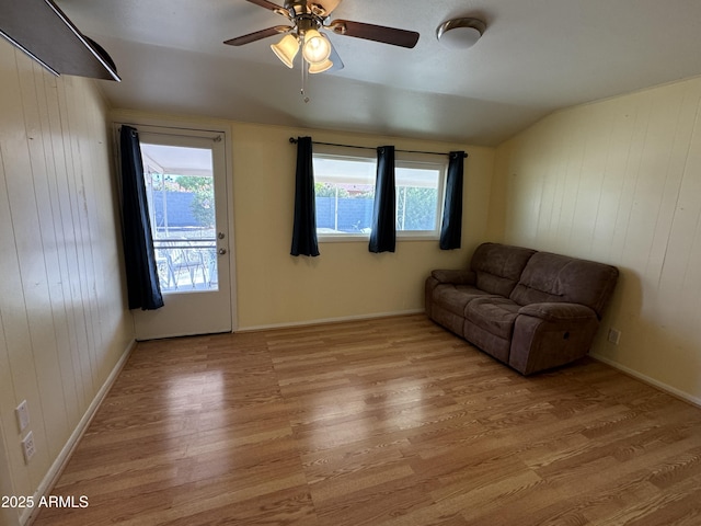 living area with lofted ceiling, ceiling fan, light wood finished floors, and a healthy amount of sunlight