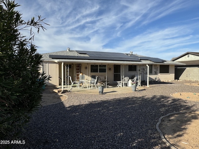 back of property featuring solar panels and a patio area