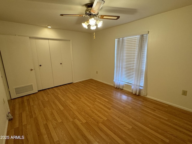 unfurnished bedroom featuring baseboards, a closet, visible vents, and wood finished floors