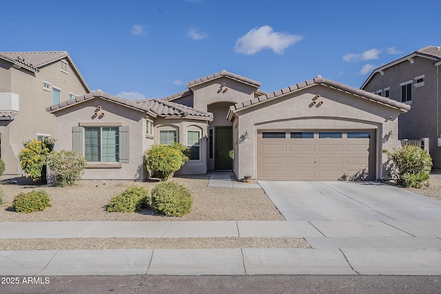 mediterranean / spanish home featuring a tiled roof, stucco siding, driveway, and a garage