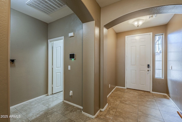 foyer with visible vents, arched walkways, baseboards, and light tile patterned flooring