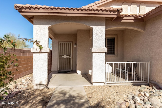 entrance to property with fence and stucco siding