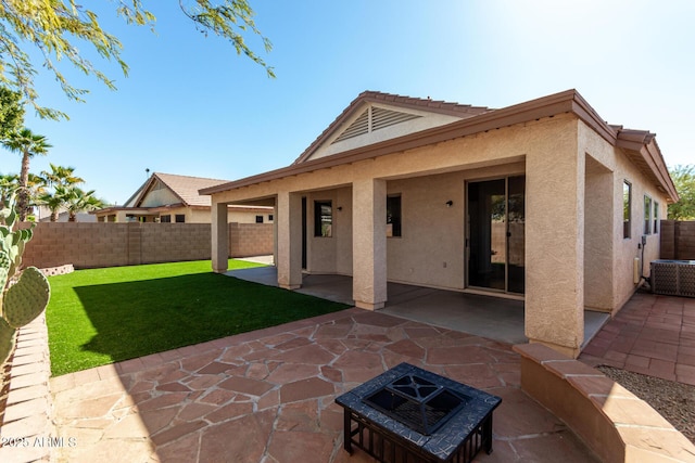 rear view of house featuring stucco siding, a fenced backyard, a lawn, and a patio