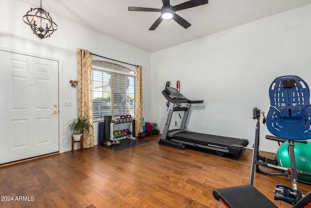 exercise area featuring wood-type flooring and ceiling fan with notable chandelier