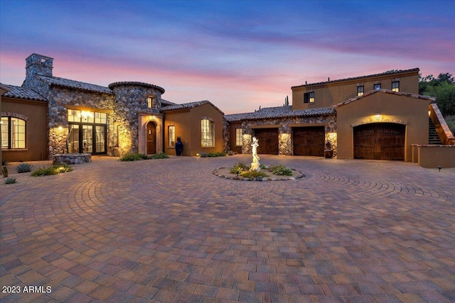9514 E Madera Dr, Scottsdale, AZ 85262 - mediterranean / spanish home with stucco siding, curved driveway, stone siding, an attached garage, and a tiled roof