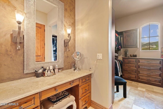 9514 E Madera Dr, Scottsdale, AZ 85262 - bathroom featuring a walk in closet, stone finish floor, vanity, and baseboards