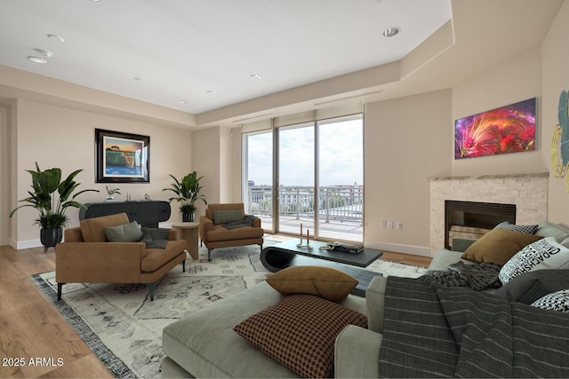 living room featuring light wood-style flooring, a fireplace, and baseboards