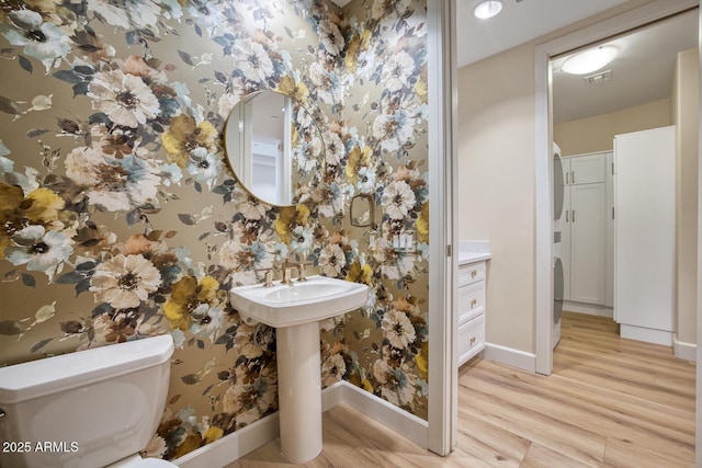 bathroom with baseboards, wallpapered walls, toilet, visible vents, and wood finished floors