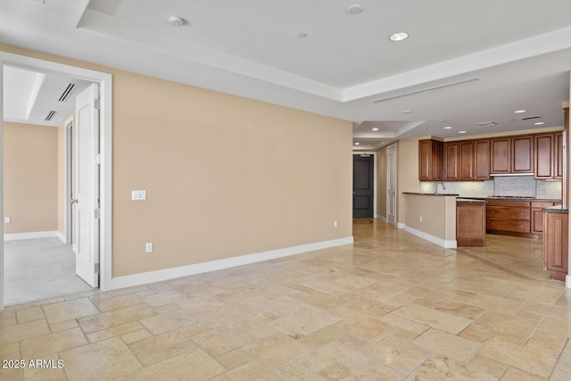 unfurnished living room with stone tile flooring, baseboards, recessed lighting, and a tray ceiling