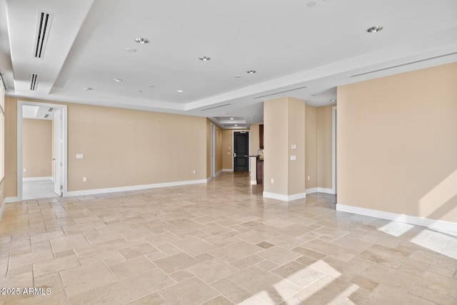 spare room with recessed lighting, visible vents, baseboards, and a raised ceiling