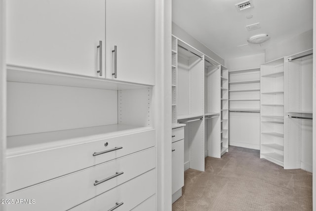 spacious closet featuring visible vents and light colored carpet