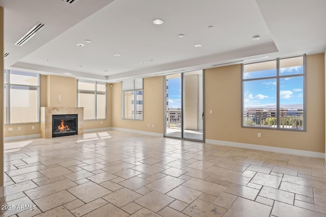 unfurnished living room with a tray ceiling, baseboards, visible vents, and recessed lighting