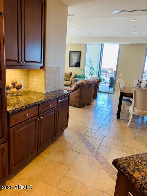 kitchen with tasteful backsplash, stone tile flooring, open floor plan, recessed lighting, and dark stone counters