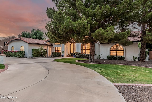 5602 W Alameda Rd, Glendale, AZ 85310 - mediterranean / spanish house with stucco siding, curved driveway, a tile roof, and a front lawn