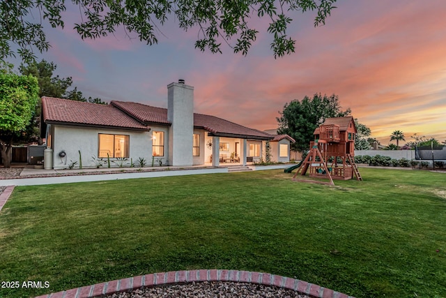 5602 W Alameda Rd, Glendale, AZ 85310 - back of house at dusk featuring a playground, a chimney, stucco siding, and a tiled roof