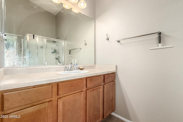 full bath featuring a stall shower, vanity, and baseboards