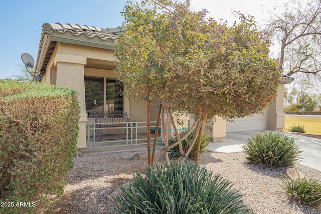 view of front of home featuring concrete driveway, a porch, a tile roof, and stucco siding