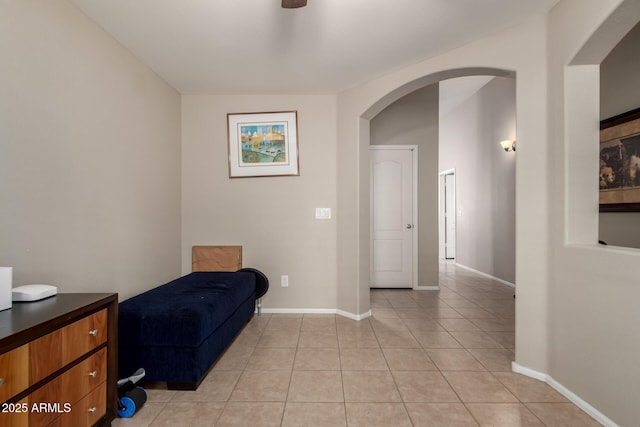 living area with arched walkways, light tile patterned flooring, and baseboards