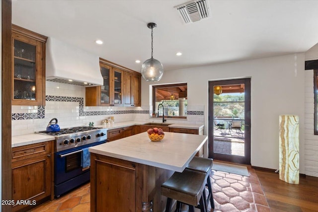 kitchen with a center island, premium range hood, sink, decorative backsplash, and high end stove