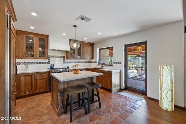 kitchen featuring a kitchen bar, custom exhaust hood, sink, decorative light fixtures, and a kitchen island