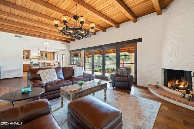 living room featuring a brick fireplace, an inviting chandelier, beamed ceiling, dark hardwood / wood-style floors, and wood ceiling