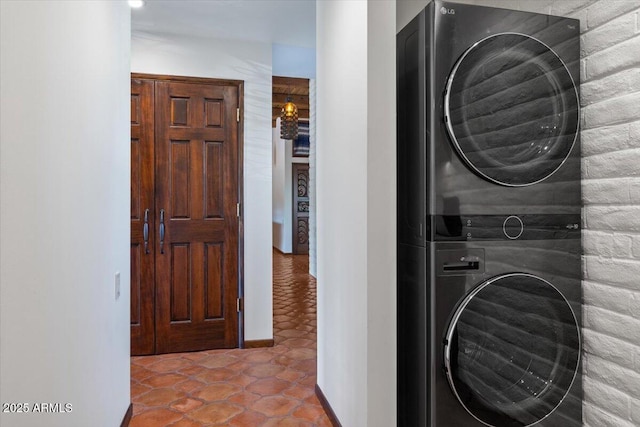 laundry room with tile patterned floors and stacked washer / dryer