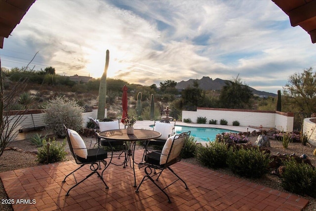 pool at dusk with a mountain view and a patio area