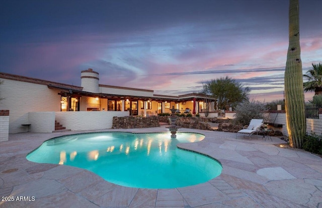 pool at dusk with a patio