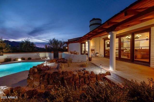 pool at dusk with a patio area