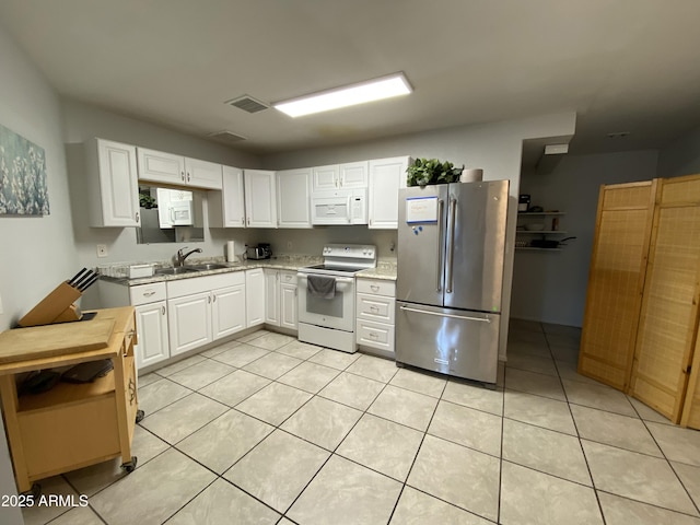 kitchen with white cabinets, light tile patterned floors, white appliances, and sink