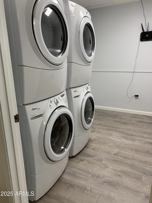 washroom featuring stacked washing maching and dryer and light hardwood / wood-style floors