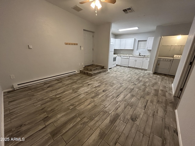 interior space with dark hardwood / wood-style flooring, ceiling fan, sink, separate washer and dryer, and a baseboard radiator