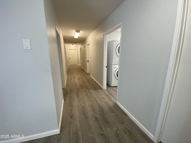 hall featuring stacked washing maching and dryer and dark wood-type flooring