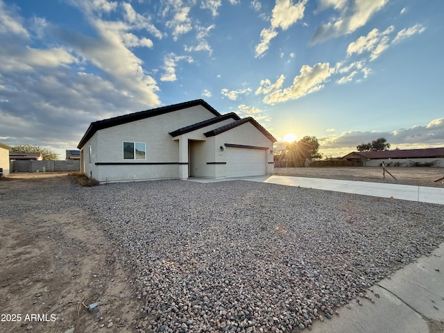 view of side of home featuring concrete driveway, an attached garage, and stucco siding