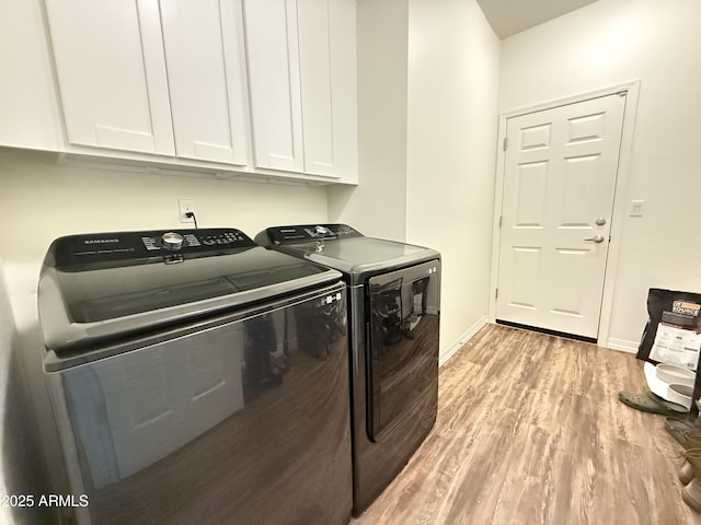 washroom with cabinet space, washing machine and dryer, baseboards, and light wood finished floors