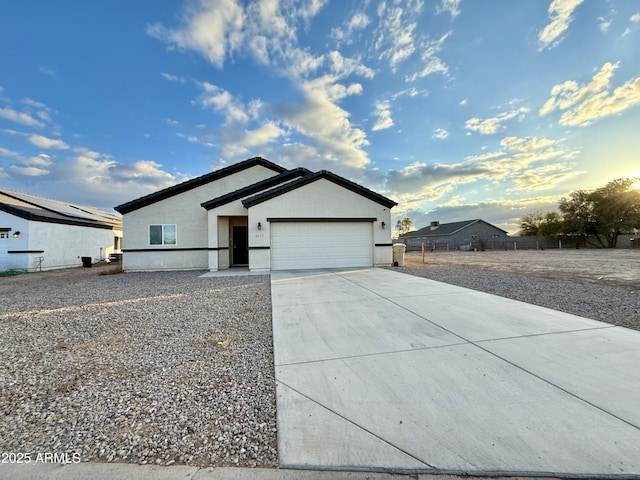 view of front facade with concrete driveway, an attached garage, and stucco siding