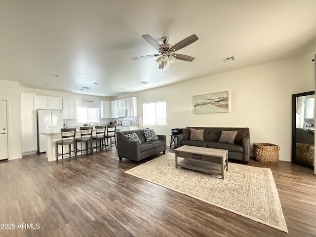 living area with dark wood-type flooring, visible vents, and a ceiling fan