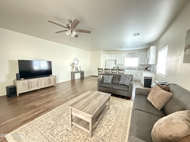 living room featuring a ceiling fan, visible vents, and wood finished floors