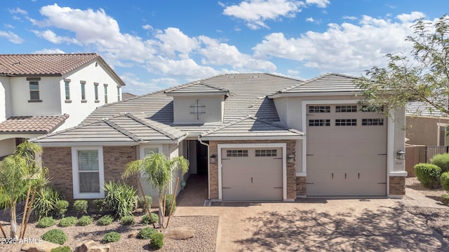 view of front facade with stucco siding, an attached garage, driveway, and a tiled roof