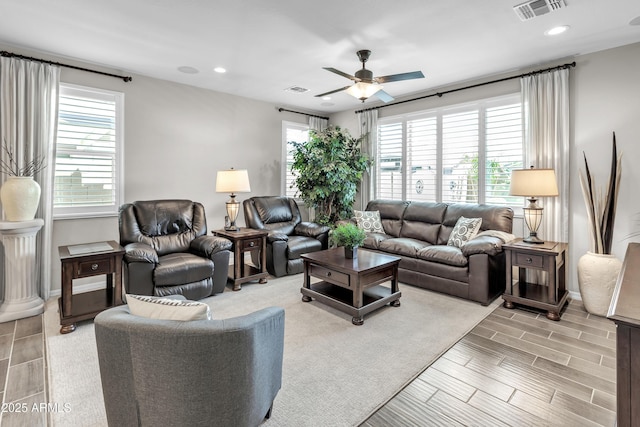 living room featuring wood finish floors, visible vents, a ceiling fan, and baseboards
