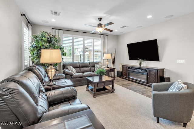 living room with a ceiling fan, visible vents, and recessed lighting