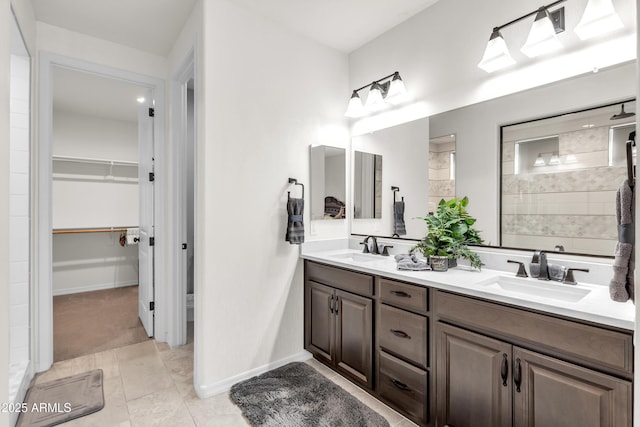 bathroom featuring double vanity, a spacious closet, baseboards, and a sink