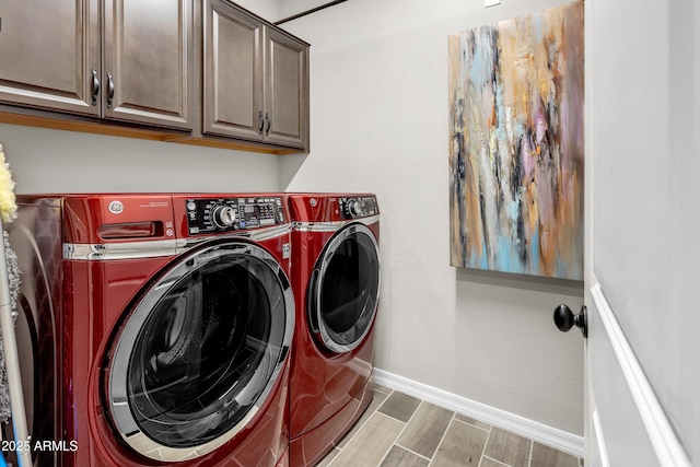 laundry area with washing machine and clothes dryer, cabinet space, wood finished floors, and baseboards