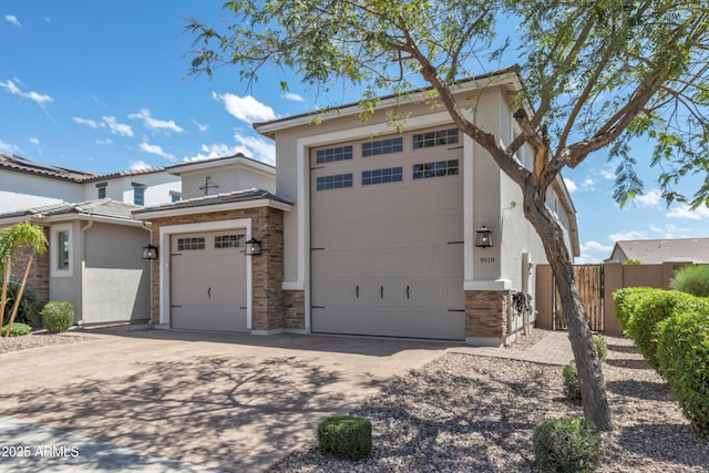 view of front of home featuring fence, stucco siding, driveway, stone siding, and a garage