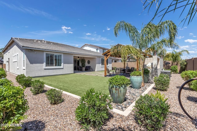 rear view of property featuring a fenced backyard, a ceiling fan, a patio area, a yard, and stucco siding